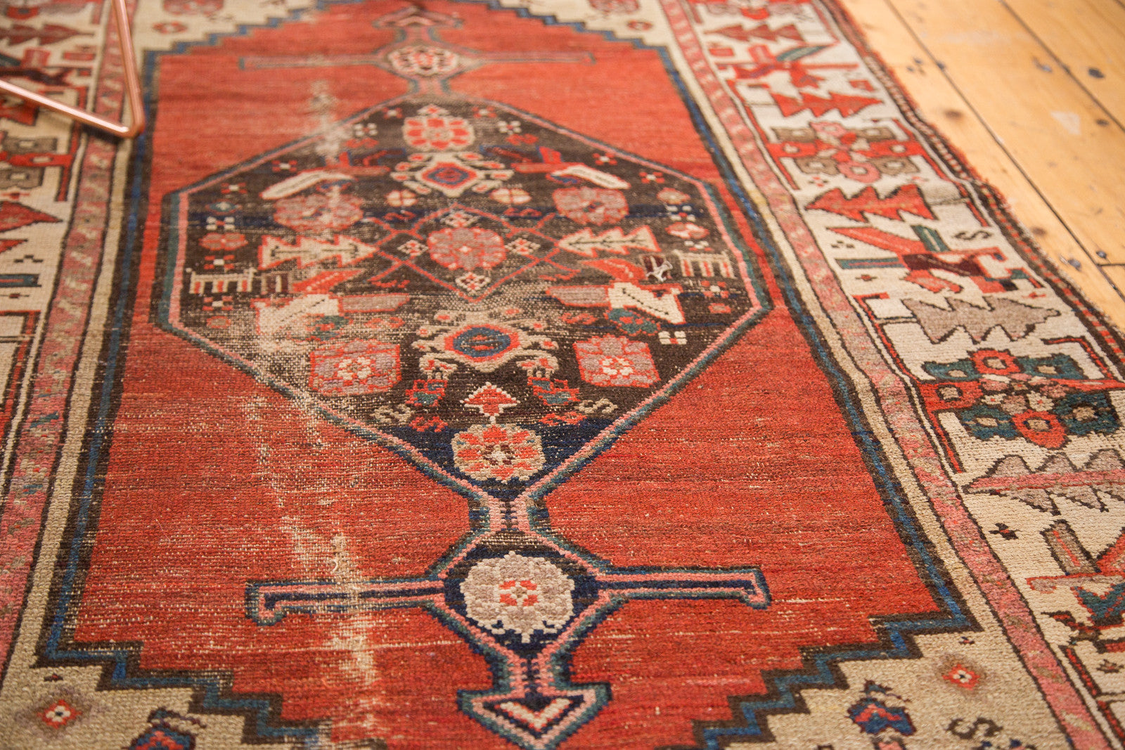 Close-up of worn madder root red pile with intricate geometric medallion detail on a vintage Kurdish rug.